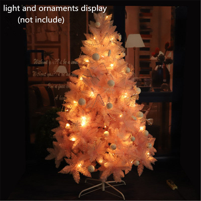 Soft pink artificial Christmas tree with warm white string lights in cozy indoor setting