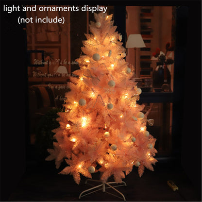 Soft pink artificial Christmas tree with warm white string lights in cozy indoor setting