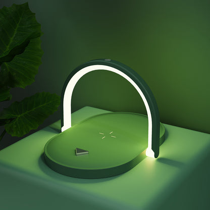 Modern green wireless charger with illuminated arch lamp on green surface and large leaves background