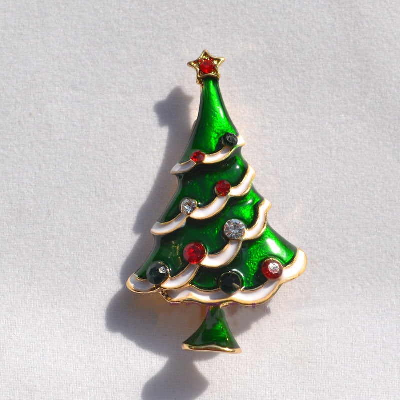 Green enamel Christmas tree brooch with red, black, and clear gem ornaments and gold star top