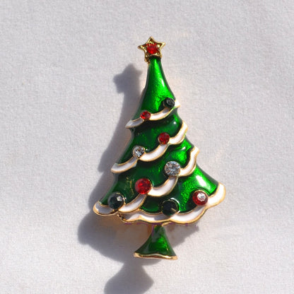Green enamel Christmas tree brooch with red, black, and clear gem ornaments and gold star top