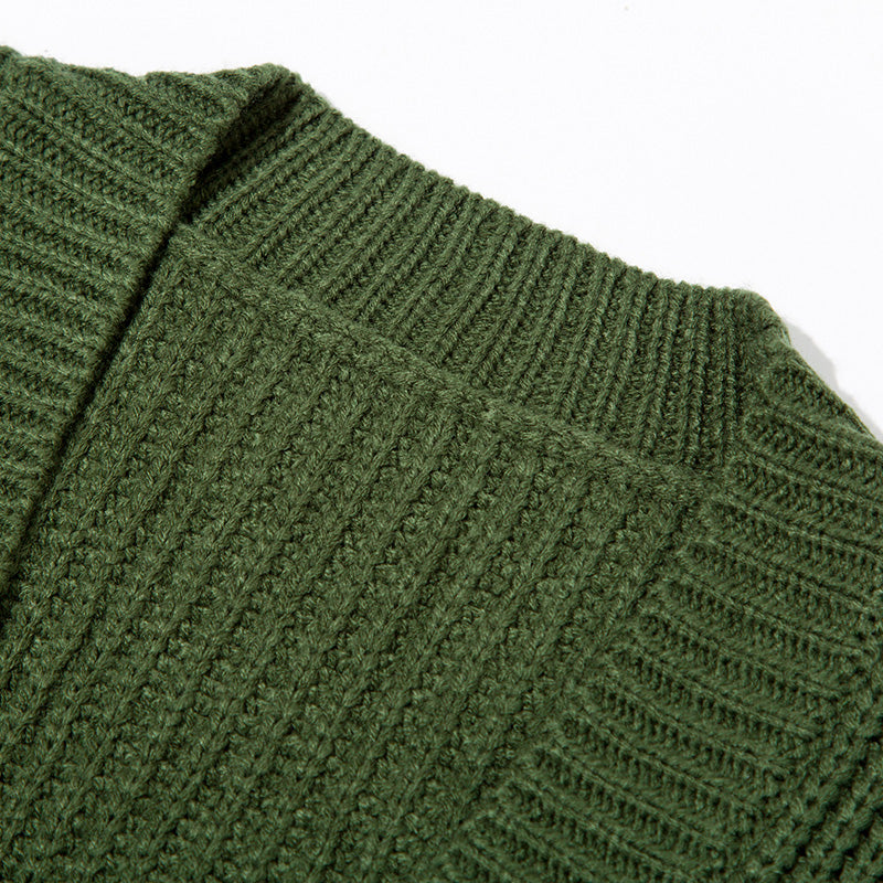 Close-up of green knitted sweater fabric showing ribbed and textured stitch patterns