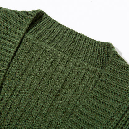 Close-up of green knitted sweater fabric showing ribbed and textured stitch patterns