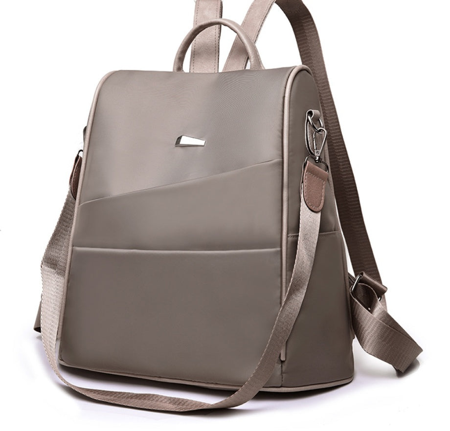 taupe nylon backpack with front pocket, top handle, and adjustable shoulder straps
