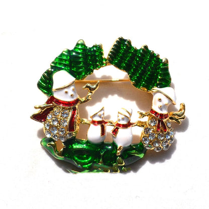 Christmas brooch featuring four white snowmen with red scarves and rhinestones, framed by green holly leaves