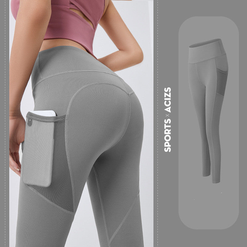 Woman wearing gray high-waisted sports leggings with side mesh pocket holding phone