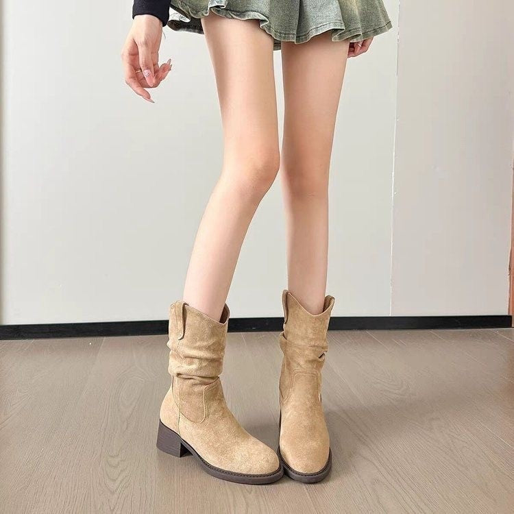 Woman wearing beige suede mid-calf boots with block heel and casual green skirt indoors