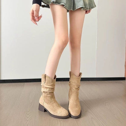 Woman wearing beige suede mid-calf boots with block heel and casual green skirt indoors