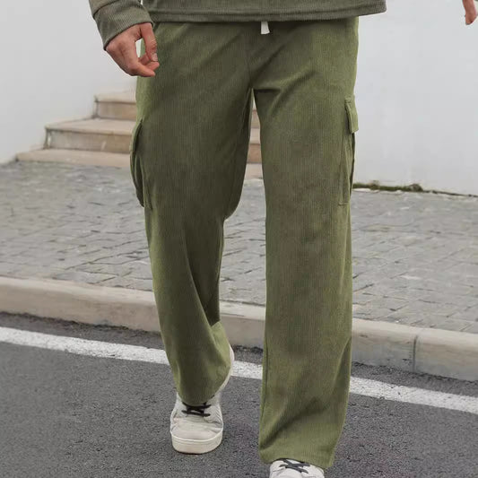 Person wearing olive green corduroy cargo pants and white sneakers walking on paved street