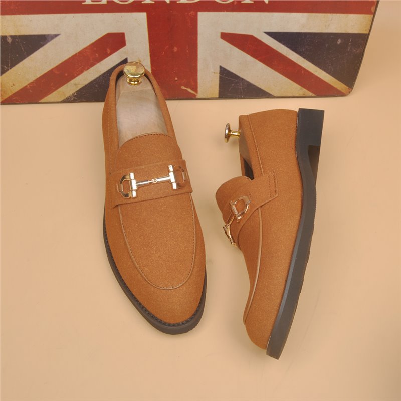 Pair of stylish brown suede loafers with gold horsebit detail and black rubber soles on beige background