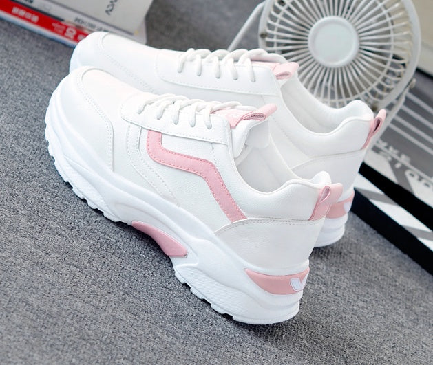 White and pink chunky sneakers on gray carpet with a small white fan in the background