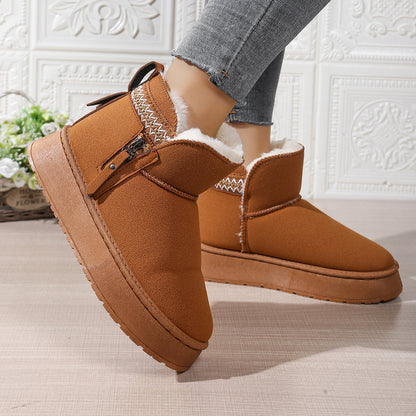 Close-up of brown suede winter boots with white fur lining and side zipper worn with gray jeans indoors