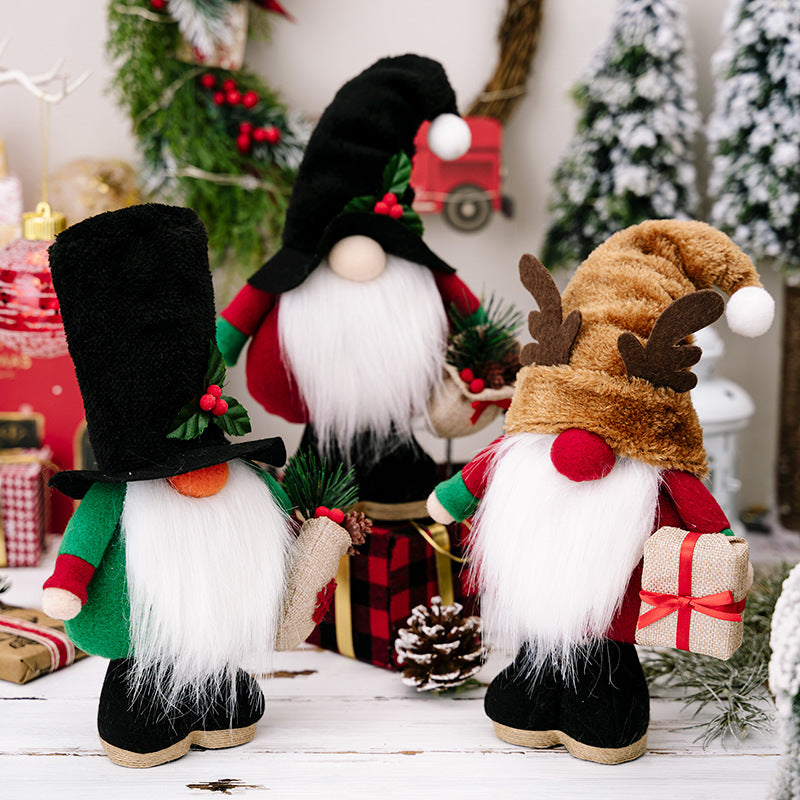 Three festive Christmas gnome dolls with white beards, colorful hats, and holiday decorations on a white wooden surface