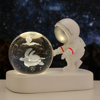 White astronaut figurine touching a glowing glass orb with a turtle and moon inside against a starry night background
