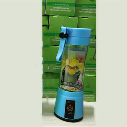 Blue portable electric blender with handle and fruit design on transparent container, stacked green boxes background