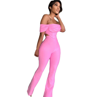 Woman in stylish pink off-shoulder jumpsuit with fitted top and flared pants on white background