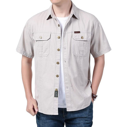 Man wearing beige short-sleeve button-up shirt with two chest pockets over white t-shirt and blue jeans