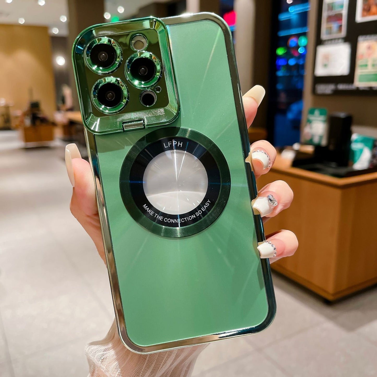 Hand holding green phone with clear protective case and triple camera lenses in modern indoor setting