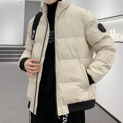 Person wearing beige padded winter jacket with black ribbed cuffs and collar, indoors
