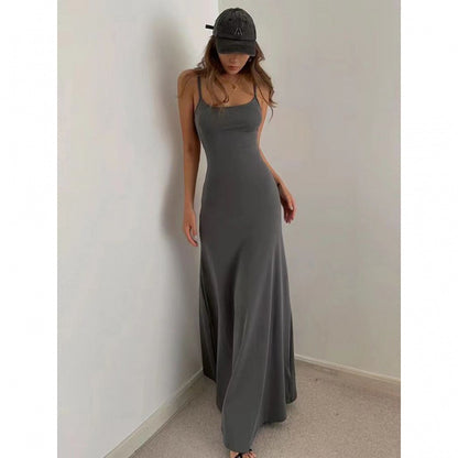 Woman wearing a fitted charcoal gray maxi dress and black baseball cap posing against white wall