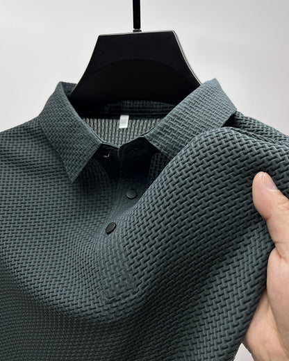 Close-up of dark gray textured polo shirt with black buttons on black hanger, hand showing fabric stretch