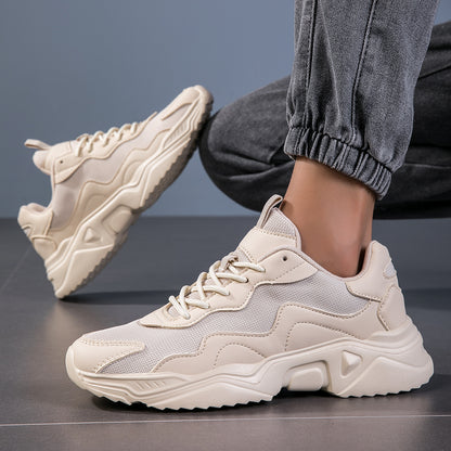 Beige chunky sneakers with textured sole worn with gray jogger pants on gray floor