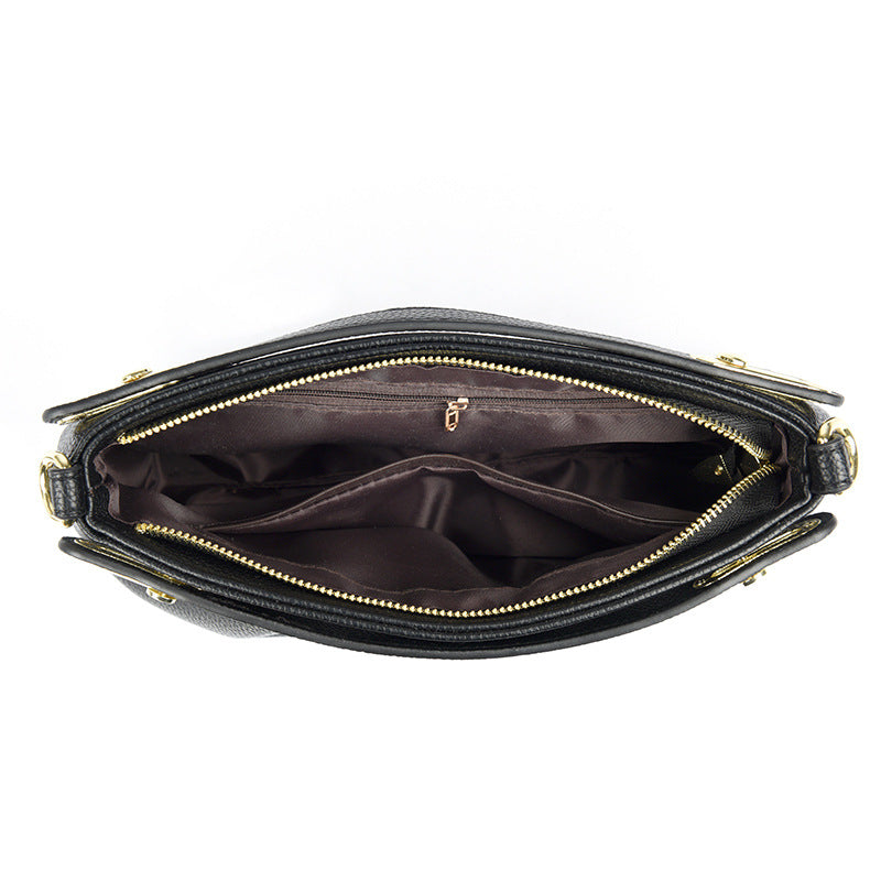 Open black leather handbag with gold zipper showing multiple inner compartments and pockets