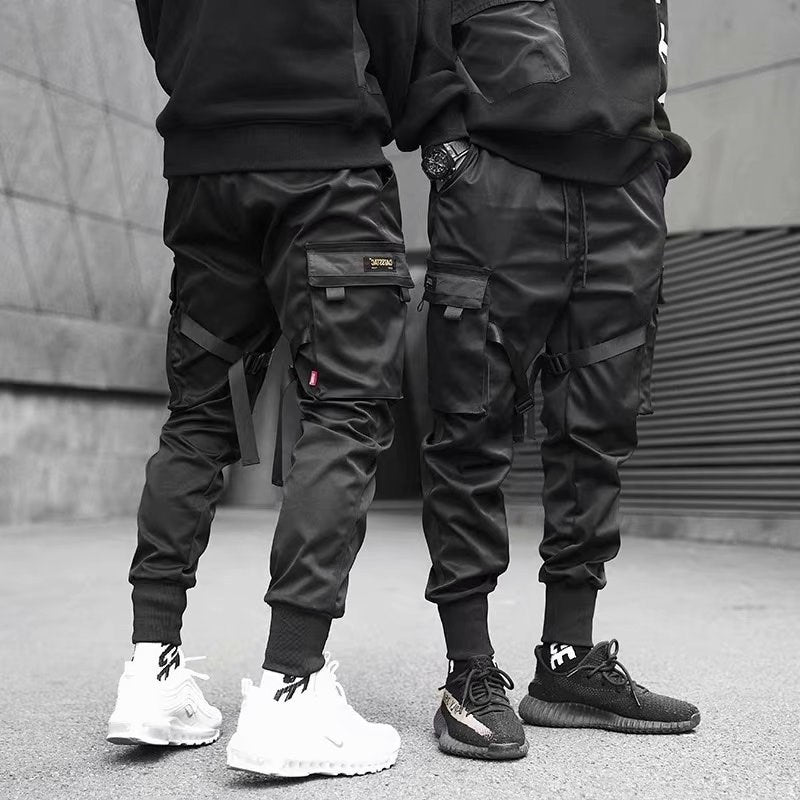 Two men wearing black cargo jogger pants and sneakers standing on urban street