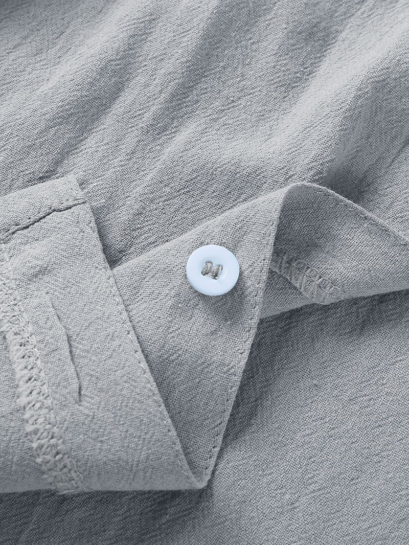 Close-up of light gray linen fabric with a white button sewn on a folded cuff