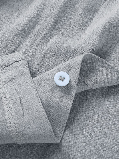 Close-up of light gray linen fabric with a white button sewn on a folded cuff