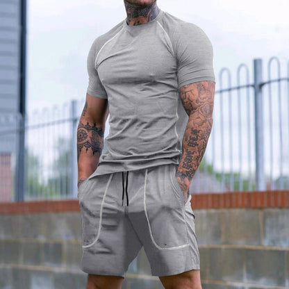 muscular man with tattooed arms wearing fitted grey short sleeve t-shirt and matching shorts outdoors