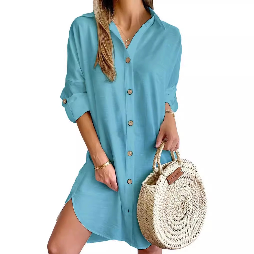 Woman in blue button-up shirt dress holding round woven straw handbag with short handles