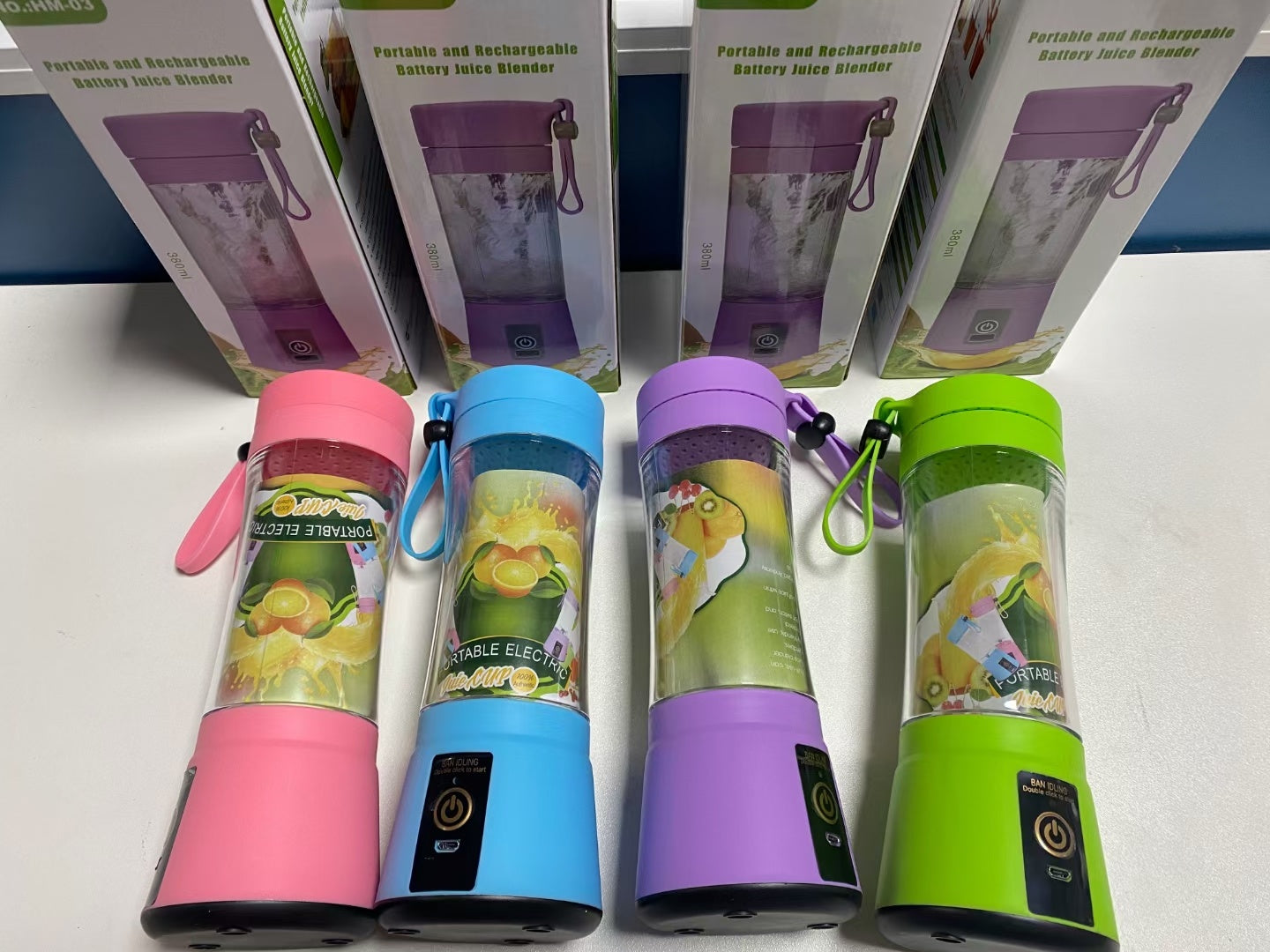 Colorful portable rechargeable battery juice blenders in pink, blue, purple, and green with carrying straps and packaging