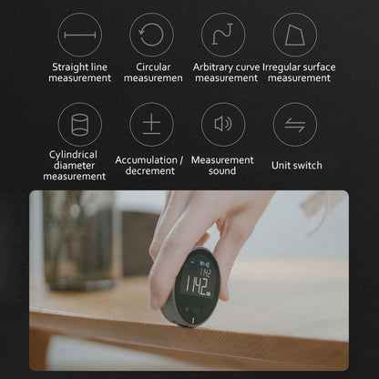 Hand holding digital measuring device on wood surface with icons for measurement modes and unit switch