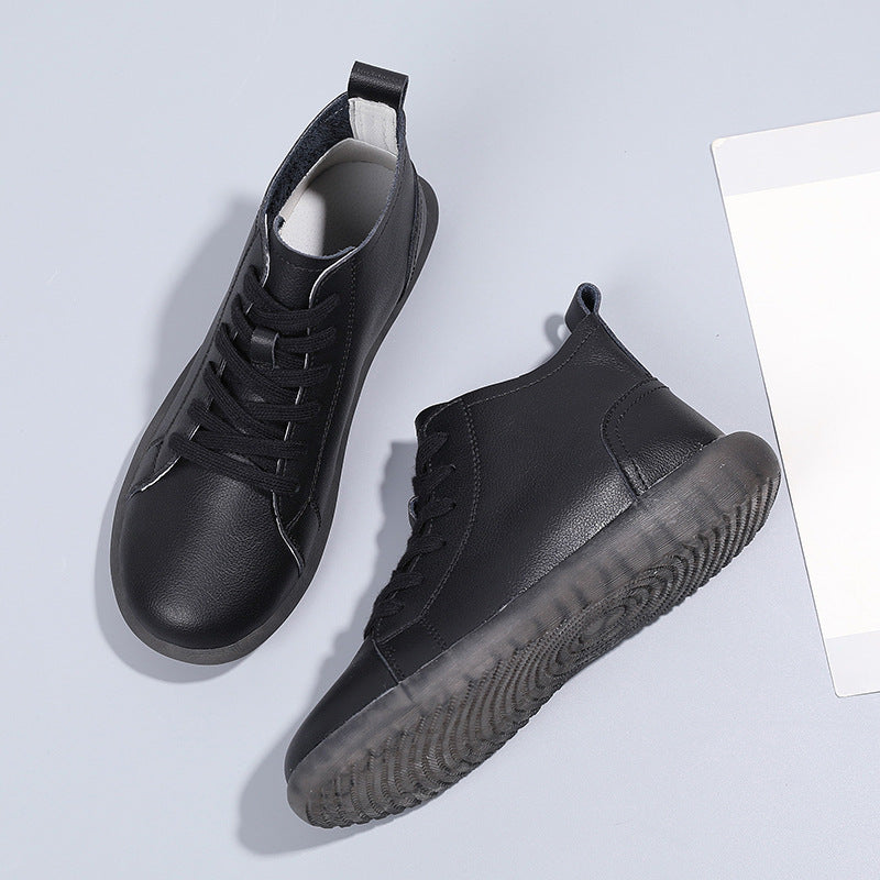 Black leather high-top sneakers with black laces and translucent rubber soles on gray background