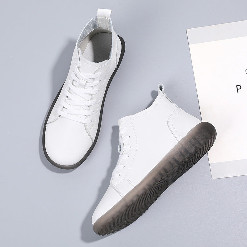 White high-top sneakers with black textured soles on gray background