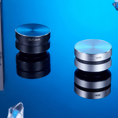 Two DuraMobi round aluminum phone holders in black and silver on reflective blue surface