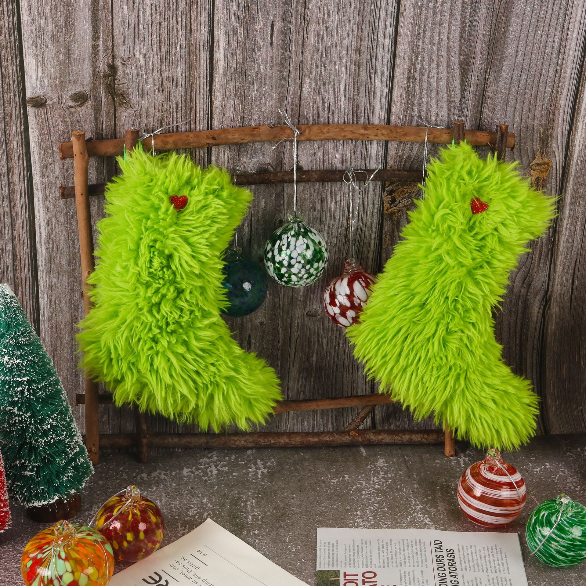 Pair of bright green fuzzy Christmas stockings with red heart accents hanging on rustic wooden frame