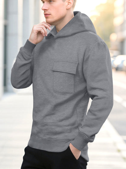 Young man wearing a gray hoodie with a front pocket standing outdoors on a city street