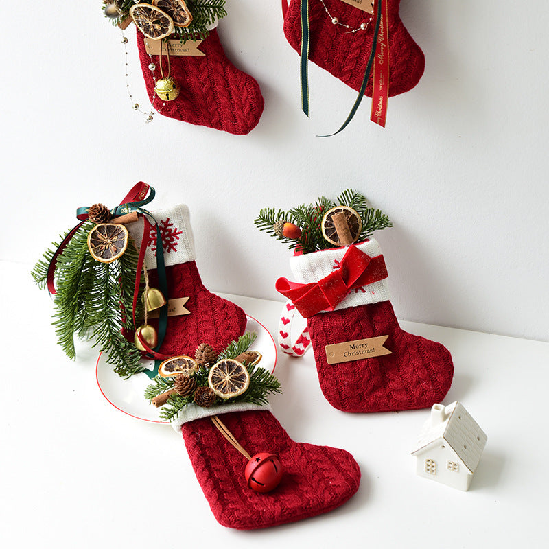 Red Christmas stockings with festive greenery, dried oranges, pine cones, bells, and ribbons on white background