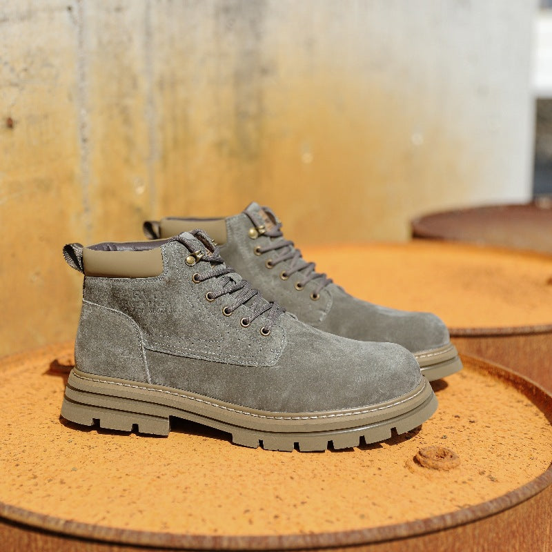 Pair of gray suede lace-up boots on rusty metal surface with textured concrete background