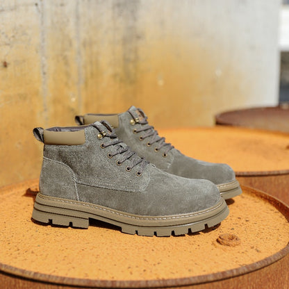 Pair of gray suede lace-up boots on rusty metal surface with textured concrete background