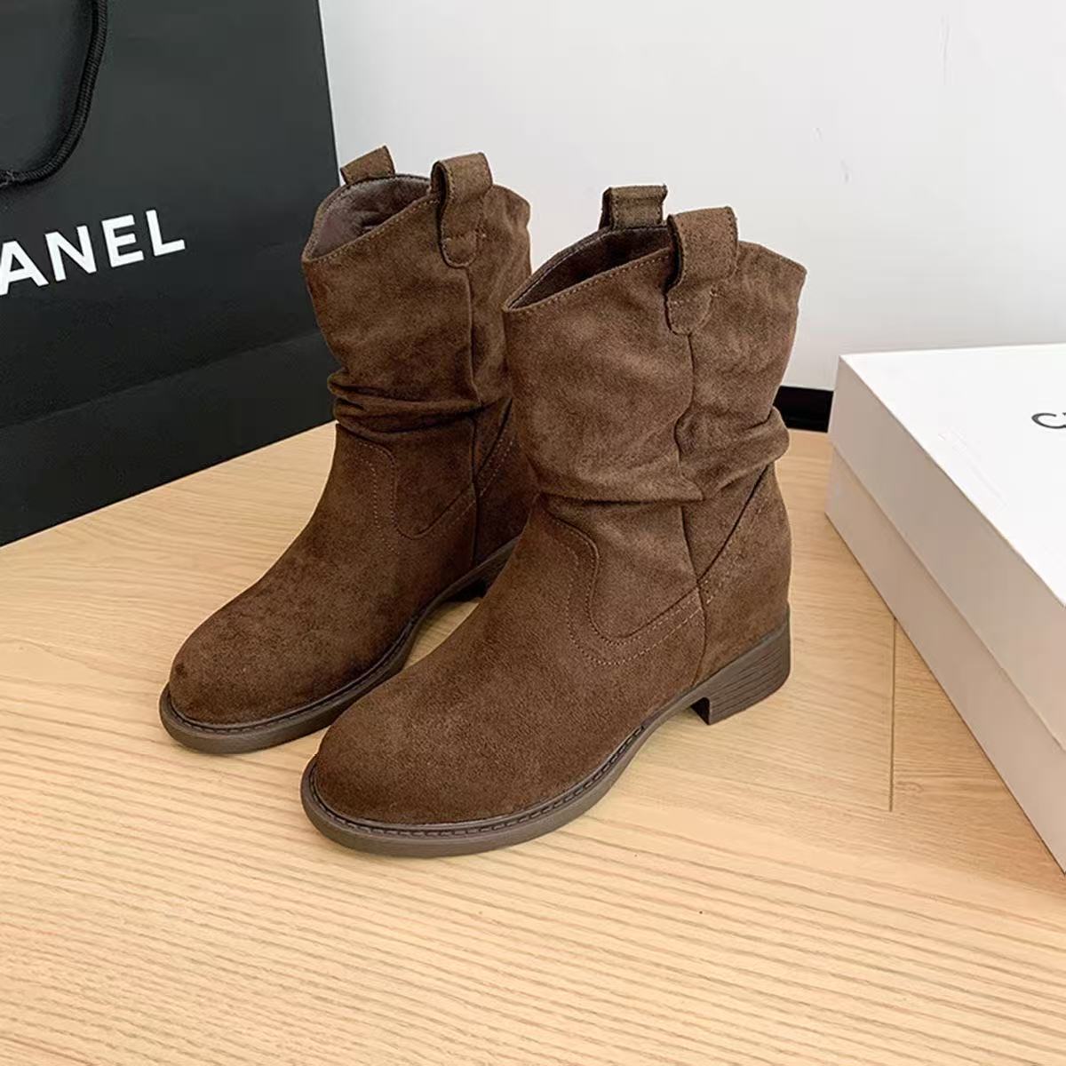 Pair of brown suede mid-calf boots with slight slouch, low block heels on wooden floor