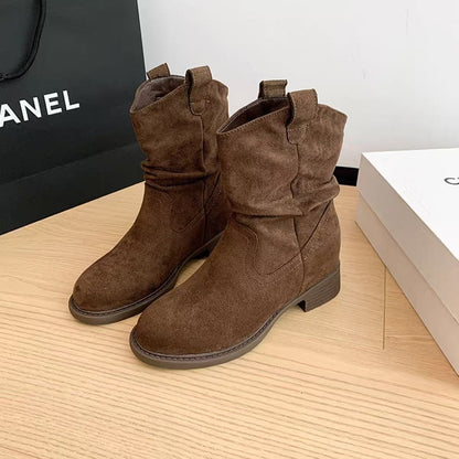 Pair of brown suede mid-calf boots with slight slouch, low block heels on wooden floor