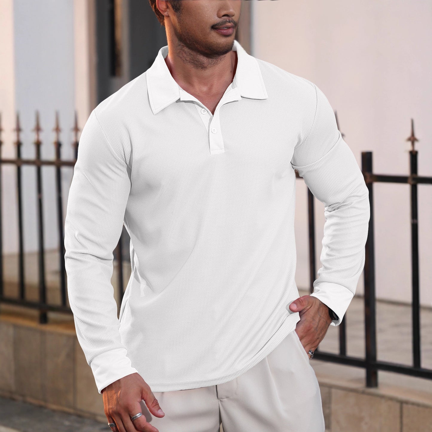 Man wearing white long-sleeve textured polo shirt and light pants, outdoor urban setting