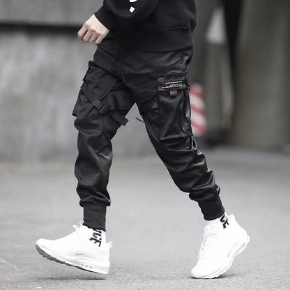 Person wearing black jogger cargo pants with multiple pockets and white sneakers walking on urban street