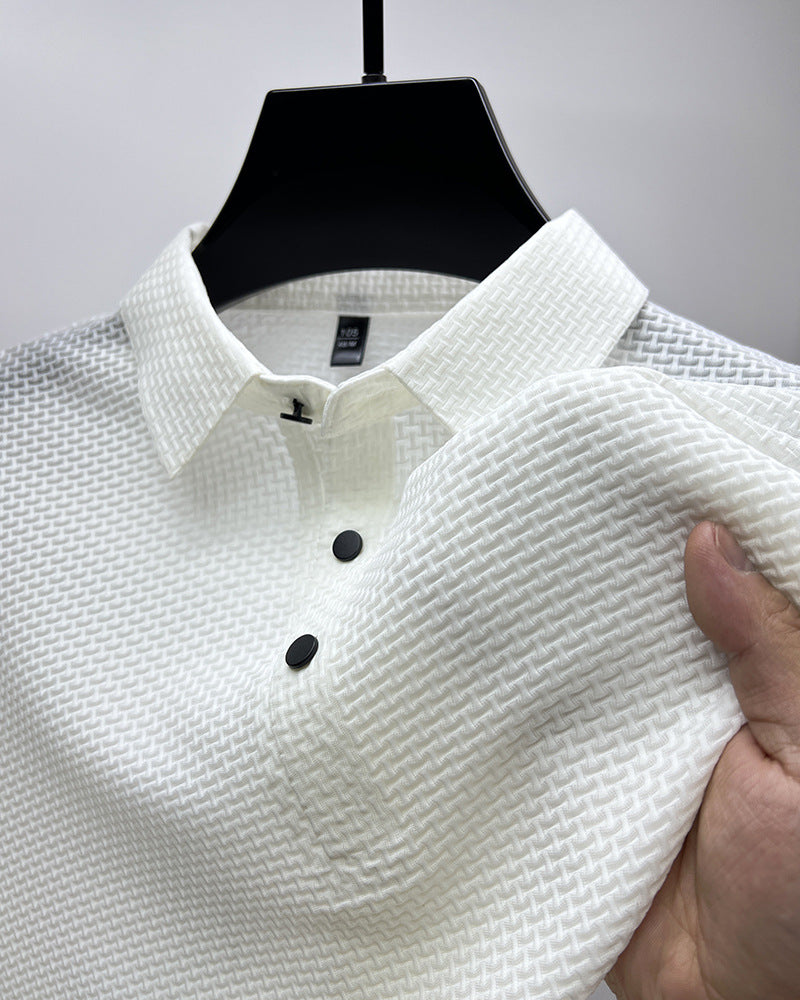Close-up of white textured polo shirt with black buttons hanging on black hanger, hand holding fabric