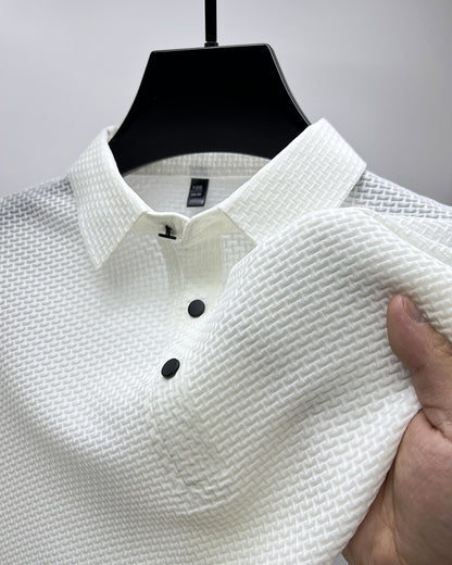 Close-up of white textured polo shirt with black buttons hanging on black hanger, hand holding fabric