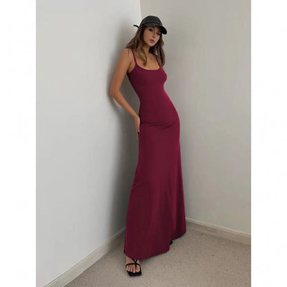 Woman wearing a fitted burgundy maxi dress with spaghetti straps, black cap, and black strappy sandals