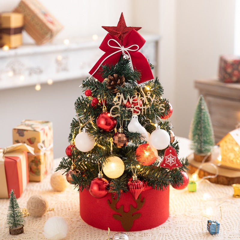 Small decorated Christmas tree with red and white ornaments, lights, and a red star on top